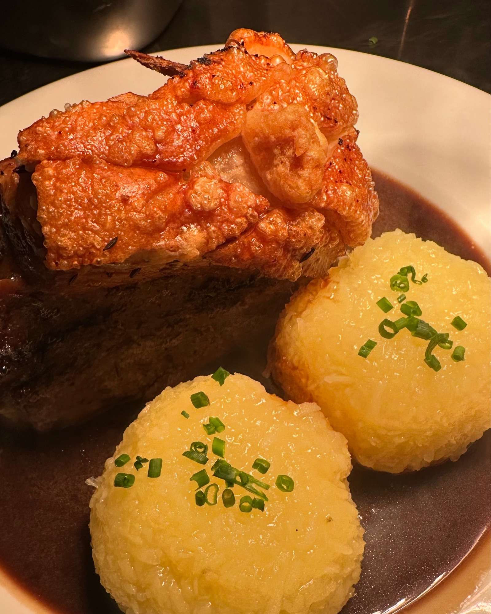 Schäufele at the Schlössla: blistered golden crackling, two potato dumplings sprinkled with herbs in dark gravy